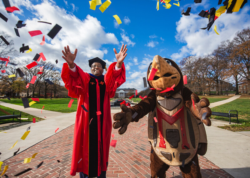 President Darryll J. Pines celebrating virtual winter 2020 commencement with Testudo mascot by throwing confetti in the air on the Mall.